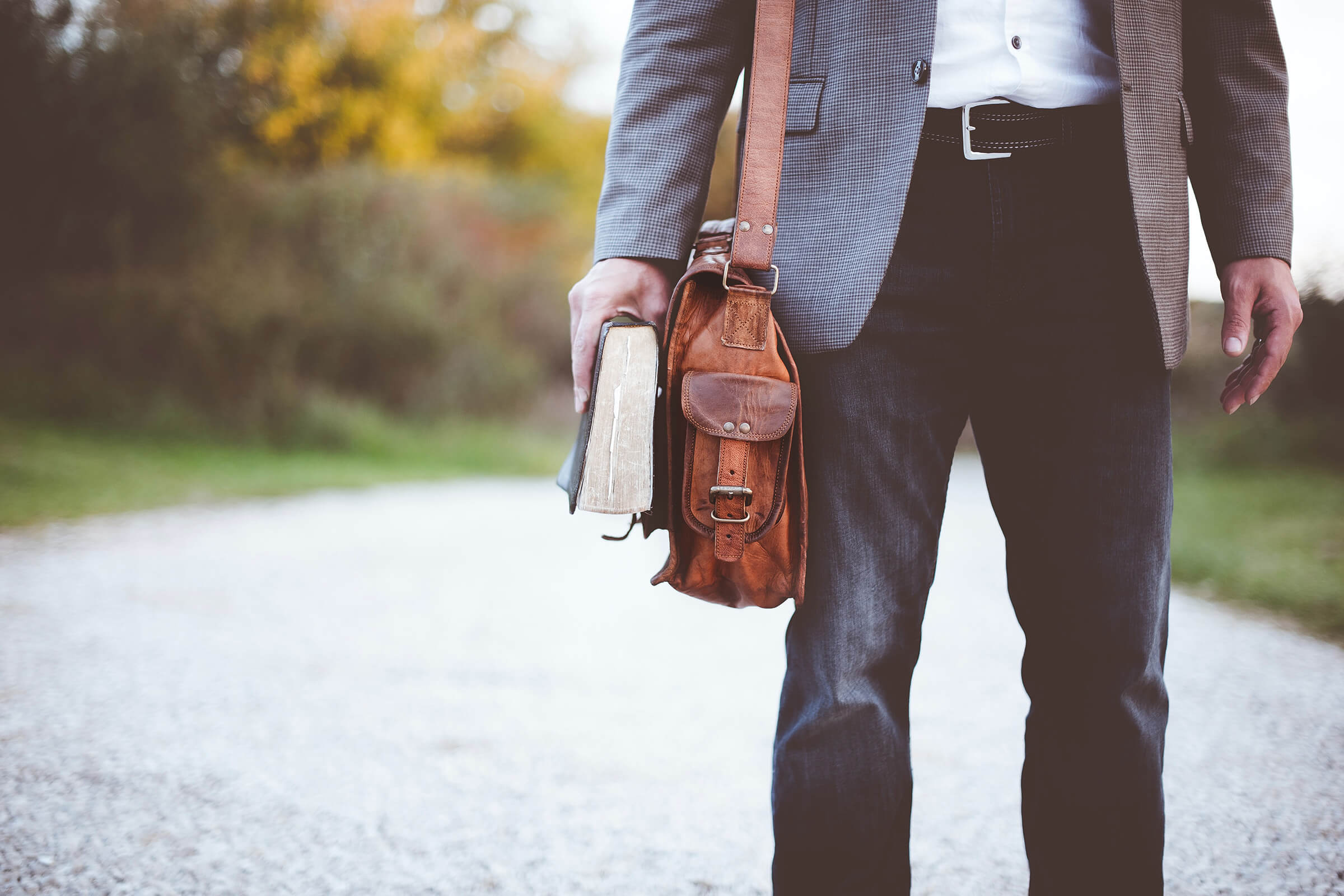 Stock photo of a man in jeans with a book and messenger bag